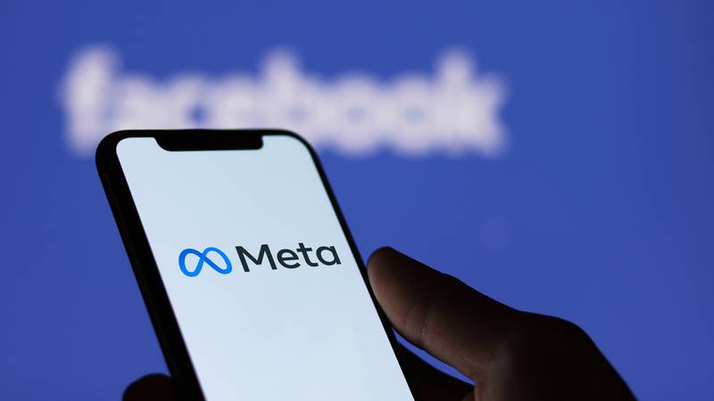 Meta logo on smartphone screen and Facebook logo  background